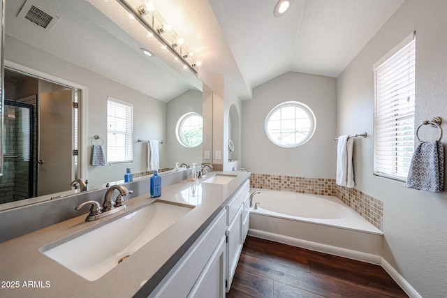 7110 N 28th Dr, Phoenix, AZ 85051 - full bath featuring wood-type flooring, plenty of natural light, vaulted ceiling, a bath, and a stall shower