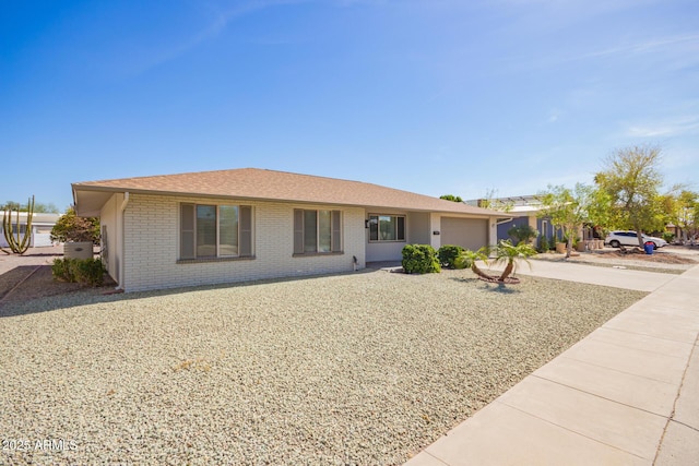 single story home with a garage, driveway, and brick siding