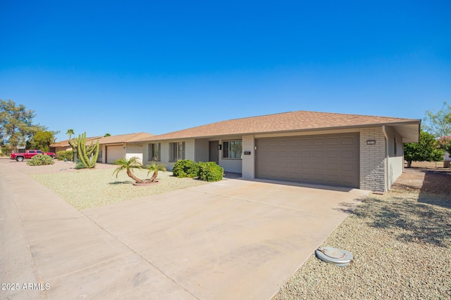 single story home featuring concrete driveway, brick siding, and an attached garage