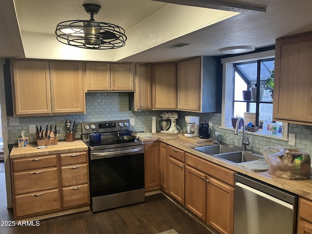 kitchen with stainless steel appliances, sink, wood counters, dark wood-type flooring, and pendant lighting