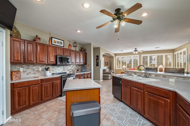 kitchen with sink, light tile patterned floors, appliances with stainless steel finishes, backsplash, and a kitchen island