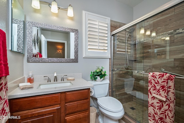 bathroom featuring a shower with door, vanity, and toilet