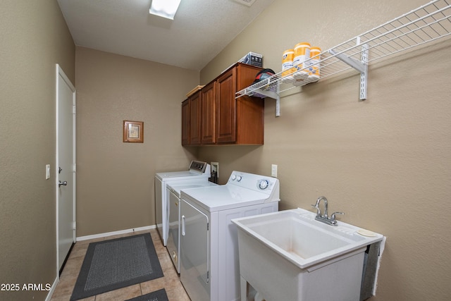 clothes washing area with light tile patterned flooring, cabinets, washer and clothes dryer, and sink