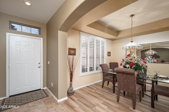 foyer with a wealth of natural light, light hardwood / wood-style flooring, and a tray ceiling