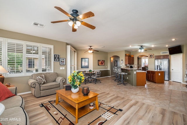 living room featuring a wealth of natural light, ceiling fan, and light wood-type flooring