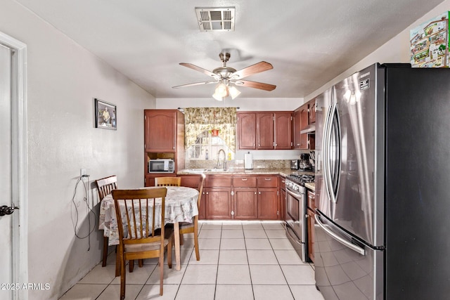 3525 W Latham St, Phoenix, AZ 85009 - kitchen with stainless steel appliances, a ceiling fan, light tile patterned floors, brown cabinetry, and light countertops