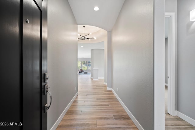 hall with an inviting chandelier and light hardwood / wood-style floors