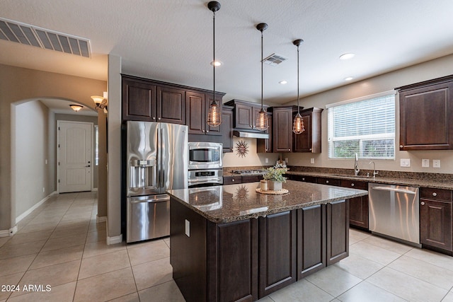 kitchen featuring stainless steel appliances, sink, pendant lighting, and a kitchen island