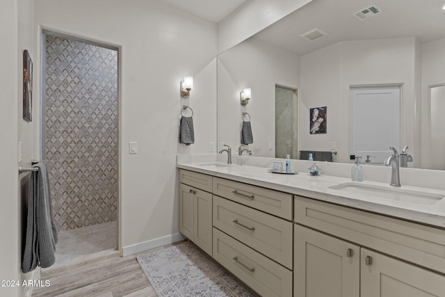 bathroom with hardwood / wood-style floors, vanity, and a tile shower