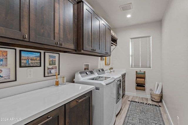 laundry room with cabinets, separate washer and dryer, and light wood-type flooring