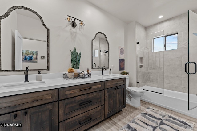 full bathroom featuring hardwood / wood-style floors, enclosed tub / shower combo, toilet, and vanity