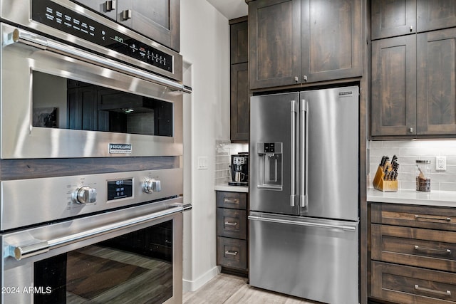 kitchen with high end fridge, dark brown cabinetry, tasteful backsplash, and light hardwood / wood-style flooring