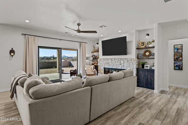 living room featuring a fireplace, light hardwood / wood-style floors, and ceiling fan