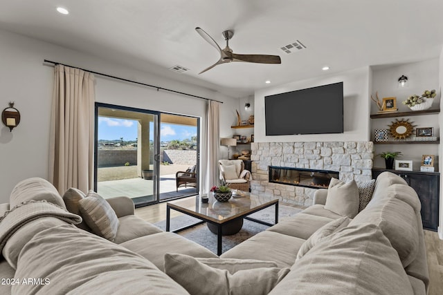 living room featuring ceiling fan, light hardwood / wood-style floors, and a fireplace