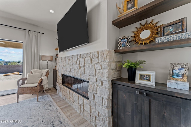 living room with a stone fireplace and light wood-type flooring