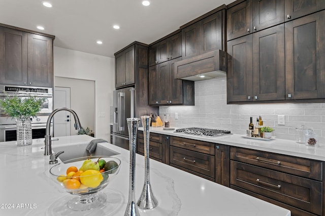 kitchen with stainless steel appliances, dark brown cabinets, and light stone counters