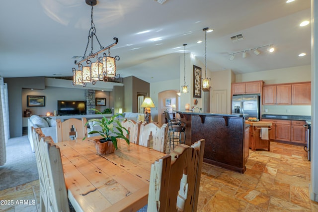 dining room featuring rail lighting and vaulted ceiling