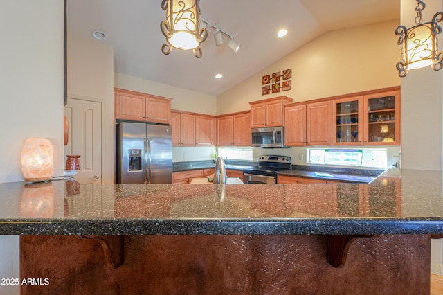 kitchen featuring kitchen peninsula, stainless steel appliances, dark stone counters, and a kitchen breakfast bar