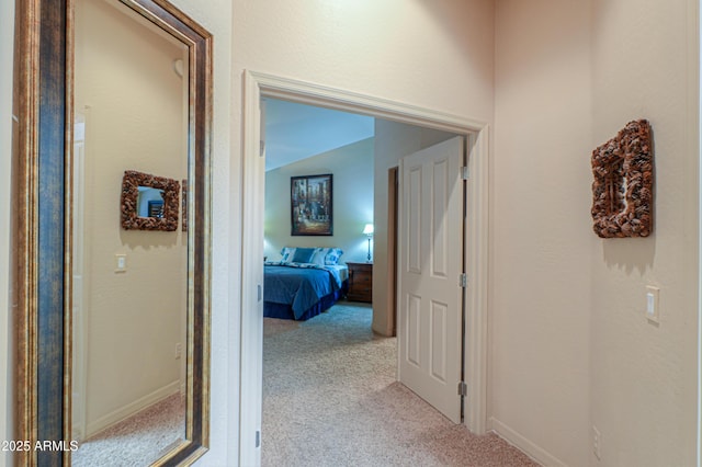 corridor with lofted ceiling and light colored carpet