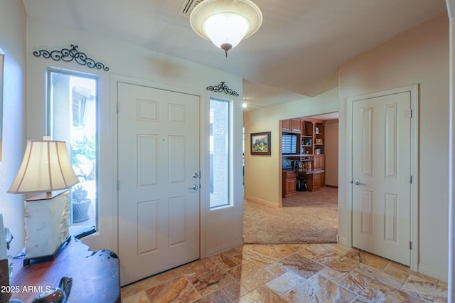 entrance foyer featuring a healthy amount of sunlight, light carpet, and lofted ceiling