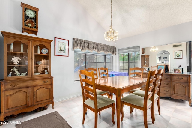 dining room with lofted ceiling, a textured ceiling, a chandelier, baseboards, and light floors