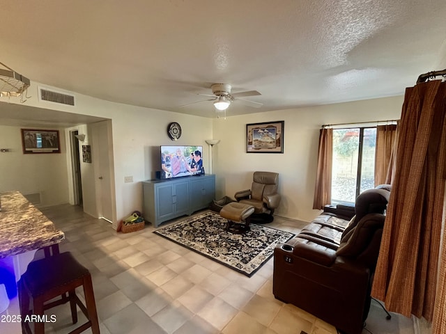 living area with a ceiling fan, visible vents, a textured ceiling, and light floors