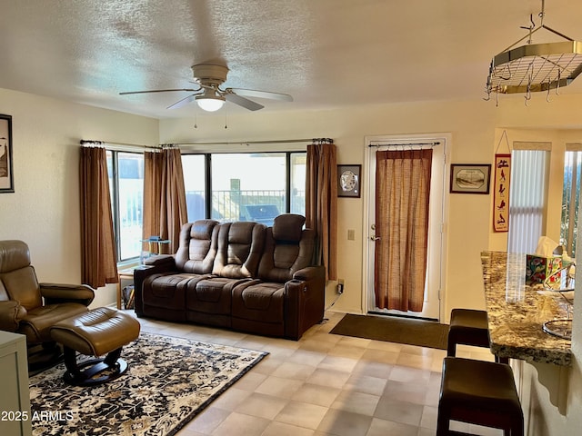 living room with light floors, ceiling fan, a city view, and a textured ceiling