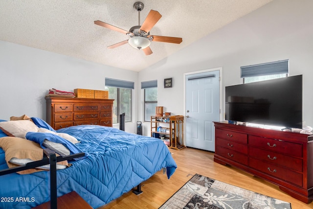 bedroom featuring a ceiling fan, lofted ceiling, a textured ceiling, and light wood finished floors