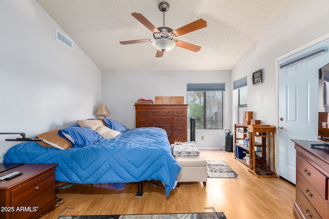 bedroom with light wood-style floors, visible vents, a textured ceiling, and a ceiling fan