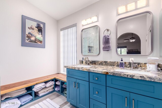 bathroom featuring double vanity, wood finished floors, a sink, and a ceiling fan