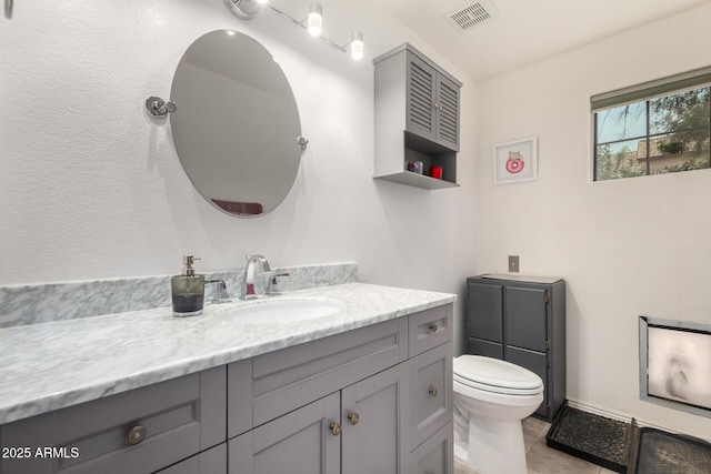 bathroom featuring toilet, vanity, visible vents, and tile patterned floors