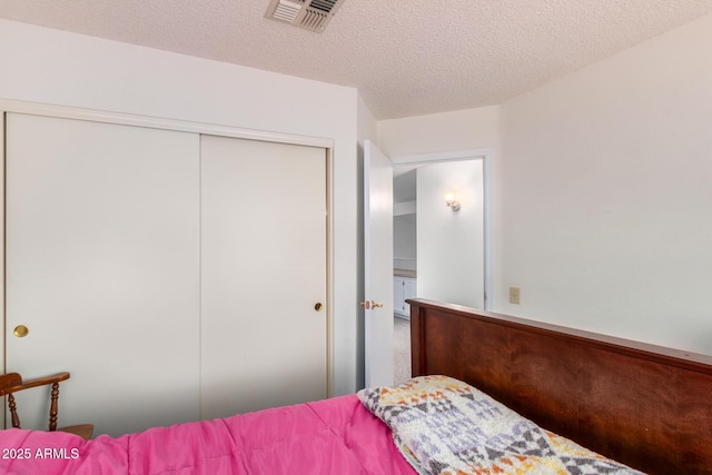 bedroom featuring a closet, visible vents, and a textured ceiling