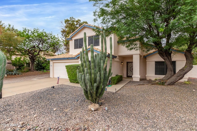 view of front of property with concrete driveway, a tiled roof, an attached garage, and stucco siding