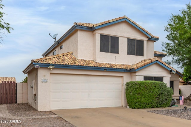 view of front of home with concrete driveway, a tile roof, fence, and stucco siding