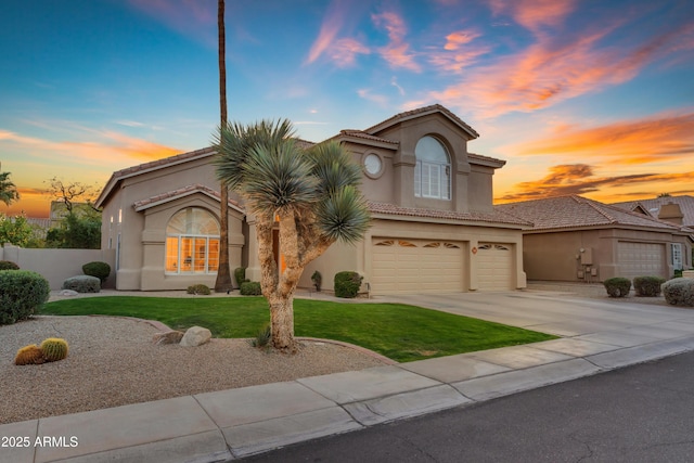 mediterranean / spanish house featuring an attached garage, a yard, driveway, and stucco siding