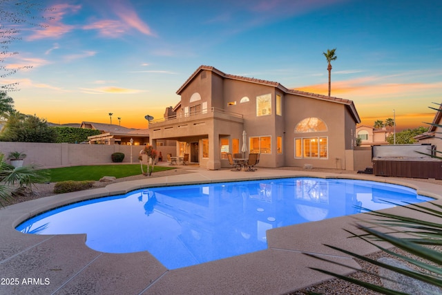 pool at dusk featuring a patio area, a jacuzzi, a fenced in pool, and a fenced backyard