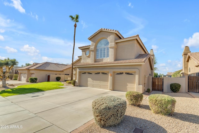 mediterranean / spanish house featuring an attached garage, driveway, a tiled roof, a gate, and stucco siding