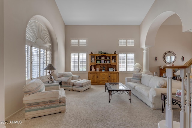 living room featuring arched walkways, carpet flooring, a towering ceiling, and ornate columns