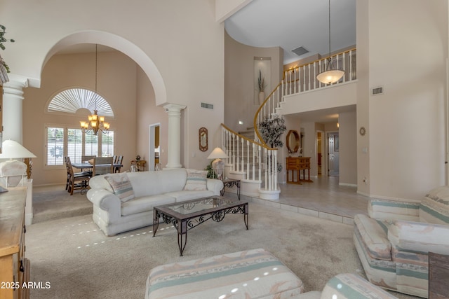 carpeted living room featuring stairway, visible vents, decorative columns, and a notable chandelier