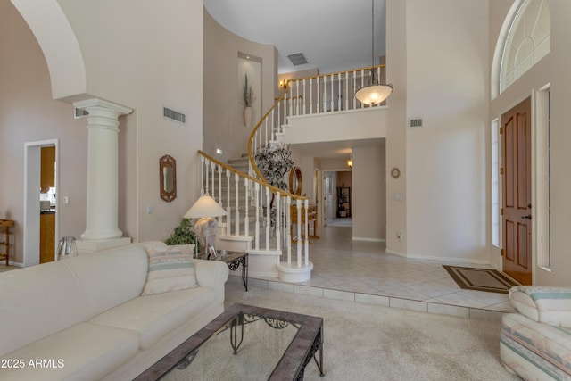 carpeted living room with visible vents, decorative columns, and tile patterned floors