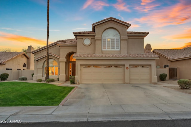 mediterranean / spanish home featuring driveway, a front yard, fence, and stucco siding