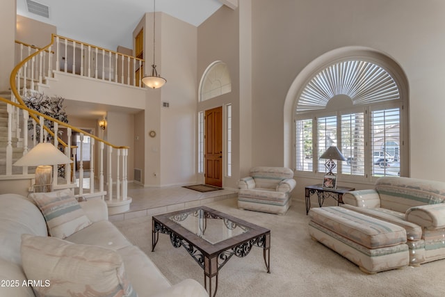 carpeted living room with tile patterned flooring, a high ceiling, visible vents, baseboards, and stairway