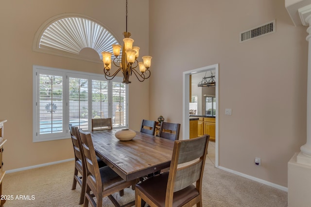 dining space with a notable chandelier, light carpet, a high ceiling, visible vents, and baseboards