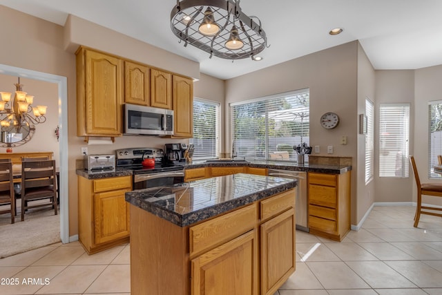 kitchen featuring a center island, tile countertops, light tile patterned floors, appliances with stainless steel finishes, and a chandelier