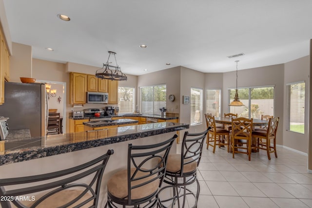 kitchen featuring visible vents, tile countertops, appliances with stainless steel finishes, a peninsula, and light tile patterned flooring