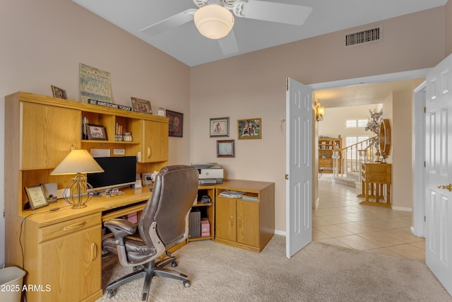 office featuring light tile patterned floors, baseboards, visible vents, a ceiling fan, and light colored carpet