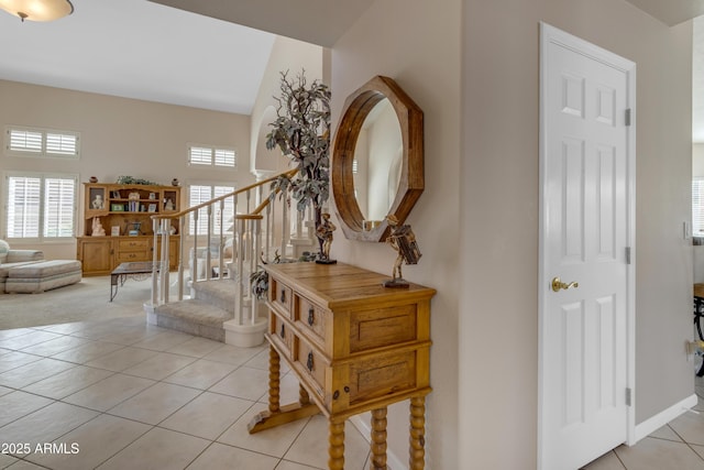 foyer entrance with light tile patterned floors, stairs, and baseboards