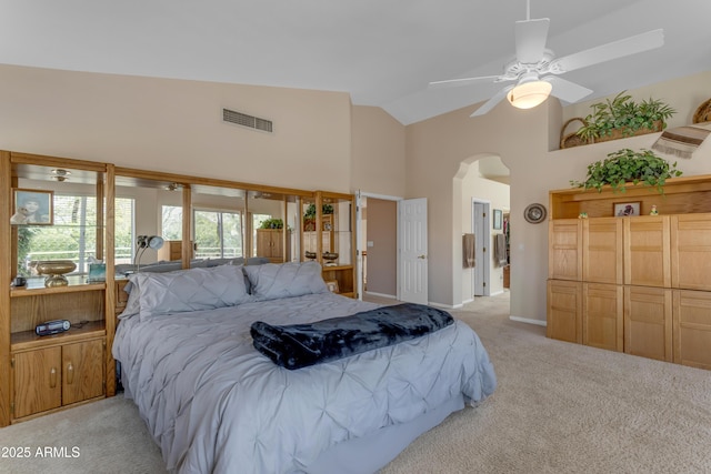 bedroom featuring arched walkways, high vaulted ceiling, light colored carpet, visible vents, and baseboards