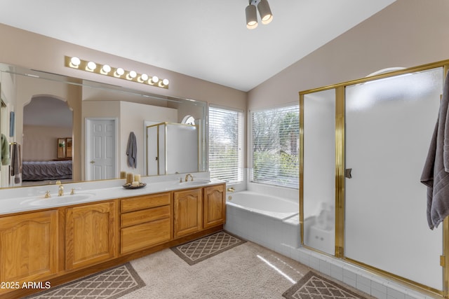 bathroom with lofted ceiling, a sink, a bath, and ensuite bathroom