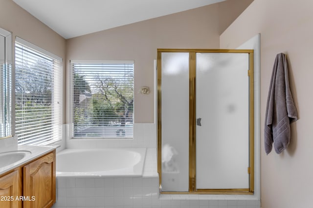 bathroom featuring a garden tub, a shower stall, vaulted ceiling, and vanity